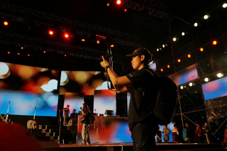 A photographer captures moments at a live music concert with vibrant stage lights.