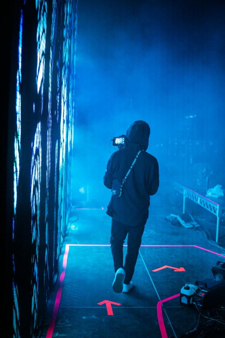Photographer capturing an atmospheric backstage scene with blue lighting and fog.